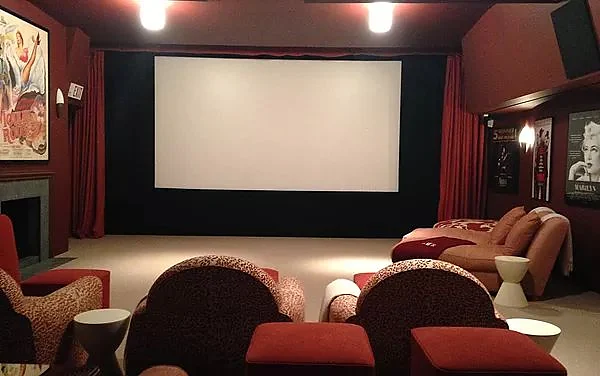 Home theater in Amagansett with red walls, movie posters and lounge seating